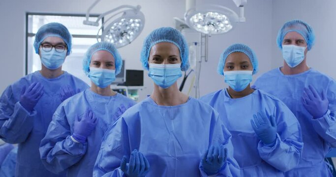 Diverse surgeons wearing face masks, surgical caps and protective clothing in operating theatre