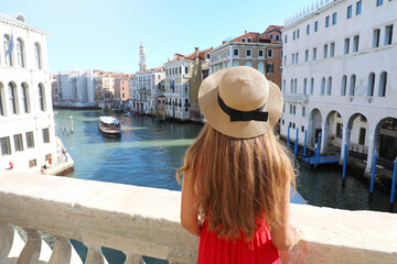 Holidays in Venice. Back view of beautiful girl in red dress enjoying view of Grand Canal from...