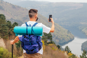 young man hiking or hiking taking pictures with mobile phone