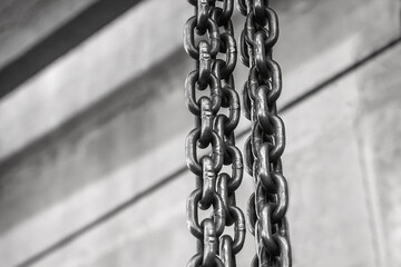 Plant equipment chain with iron links of the lifting mechanism of an overhead crane against the background of an industrial workshop or factory - Powered by Adobe