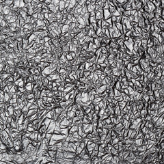 Crumpled shiny metal foil texture or black and white background for design. Abstract drawing on a thin sheet of aluminum foil.