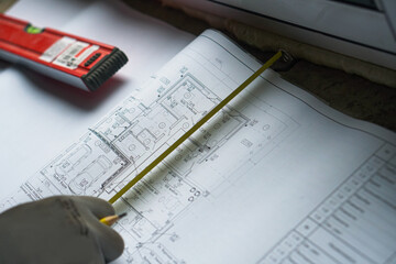 Male hands, architectural construction drawings, tape measure. The concept of architecture, construction, engineering, design.