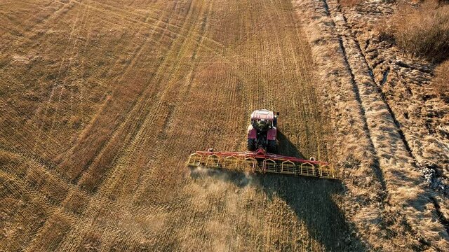 farm tractor with cultivator works the field aerial video