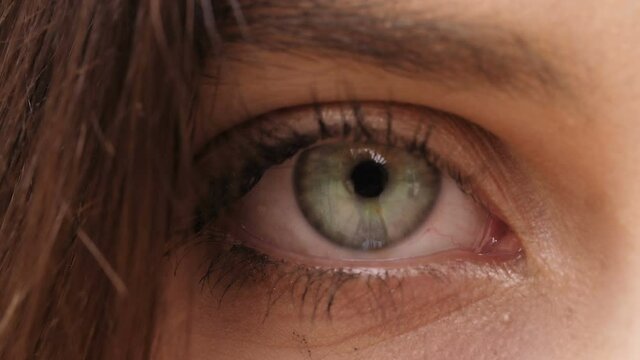 detail of woman's eye opens and stares at the camera - macro