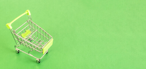 Top view of Empty shopping cart on green background, buy and sell concept.