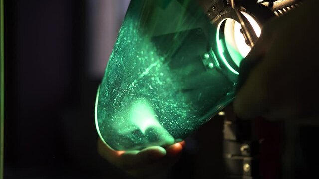Man, cameraman, director puts green colored plastic square filter metal curtain halogen light. Film set, filming movie, music video, content creation, large, large production, change production series