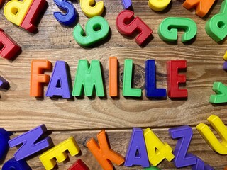 mot famille en français avec des lettres sur un fond bois - obrazy, fototapety, plakaty