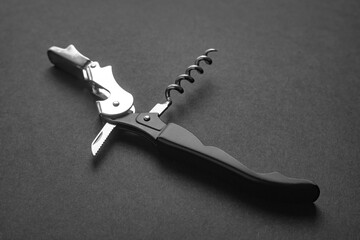 Opened sommelier knife with corkscrew and bottle opener, professional waiter knife, on black background