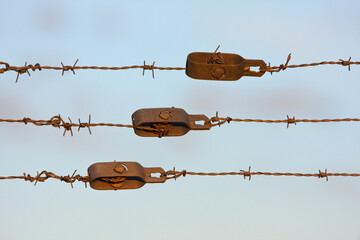 Lines of rusty barbwire with blue sky