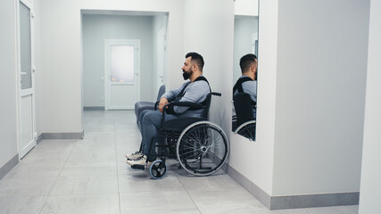 Man with disability waiting in clinic corridor