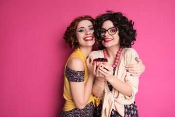Two cute girl friends woman looking like nerd accountants standing on a pink background. They wear...