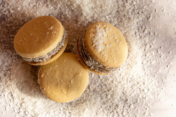 Deliciosos alfajores de maicena rellenos de dulce de leche y espolvoreados con coco rallado, a luz de la mañana.