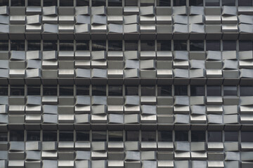 A grey facade of a modern office business high-rise building with rows of windows and plenty of...