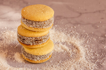 Deliciosos alfajores de maicena rellenos de dulce de leche y espolvoreados con coco rallado, a luz de la mañana.