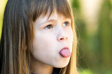 Fototapeta premium Close up portrait of cute girl showing tongue.