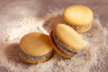Deliciosos alfajores de maicena rellenos de dulce de leche y espolvoreados con coco rallado, a luz...