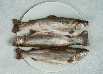 Fresh raw trout fish on a plate.Top view.White marble background..