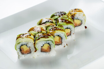 sushi rolls with fish and hard cheese, garnished with avocado and teriyaki sauce.