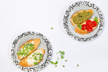 Two plates with different types of bruschetta on a white background. Overhead, Copy space, horizontal
