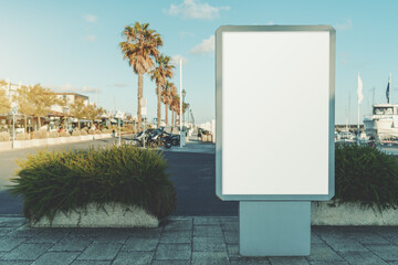 Mockup of a vertical blank ad poster in urban settings near docks and lined palm trees