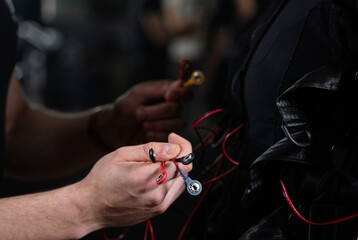 Wires from EMS suit in gym. Sport training in electrical muscle stimulation suit. Making physical exercises