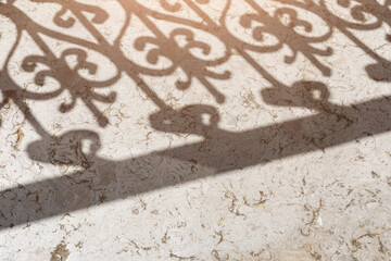 Shadow of the balcony grating on the stone floor. Fence grid in reflection