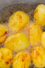 Golden potatoes are fried in boiling oil in a cauldron
