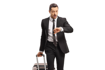 Young businessman with a suitcase going on a business trip and looking at his watch