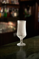 frozen glass stands on a green bar counter against a dark background