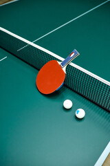 a red pinpong racket with two balls lies on a tennis table