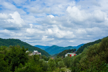 Fototapeta na wymiar Resort village in mountain valley against the blue sky with clouds, summer landscape