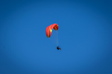 Paraglider With Red Parachute Wing Flying in a Blue Sky With Clouds