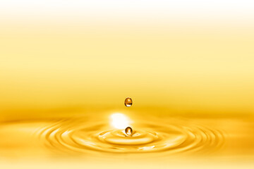 Macro shot of droplets splash of a golden elixir for beauty and body care creating circular waves...