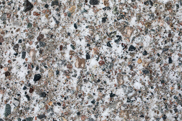 Gravel road with black and red rocks covered with a dusting of snow