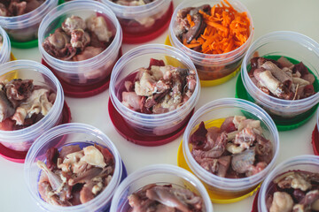 Process of preparing bowls with natural raw pet dog food at home, preparation of healthy raw barf for cats dogs, with duck, turkey, offals, meat, vegetables, assorted fresh food portions in containers