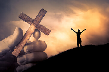 Woman looking to god with arms up to the sky feeling happy and free. Hand holding cross. Salvation, and religious belief. 
