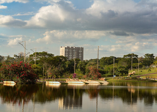 Urban park landscape with buidings, trees, clouds on the blue sky and reflections on the water's lake. Parque das Na&ccedil;&otilde;es Ind&iacute;genas, em Campo Grande, Mato Grosso do Sul, Brasil or Brazil.