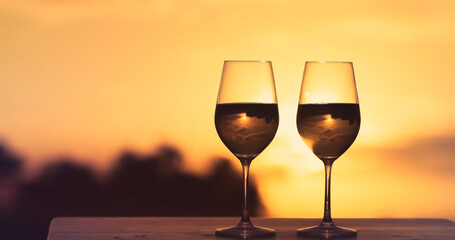 Pair of two wine glasses on table at sunset. 