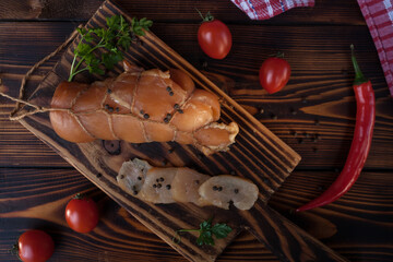 Chicken fillet with herbs, paprika and tomatoes. Traditional Ukrainian snacks, cutting board, cold smoked meat cutting on a black plate. View from above. 