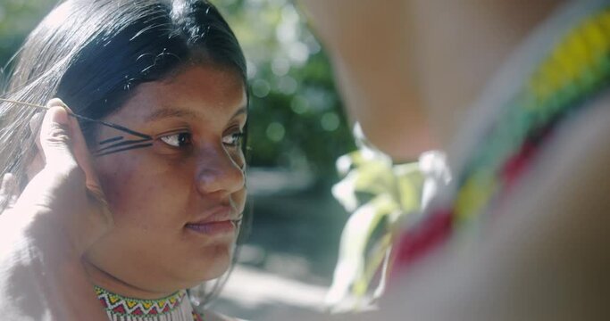 Young Brazilian girl indigenous Patax&oacute; ethnicity doing face painting. 4K.
