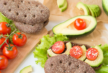 Healthy food. Avocado Sandwich. Rye bread with bran, Cherry Tomatoes, Avocado,Lettuce and Sesame Seed