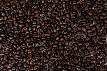 Close up of dark brown roasted whole coffee beans textured background 