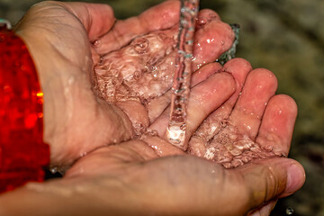 Hands splayed under a tap with water falling on them