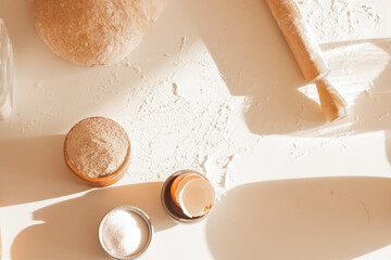 Dough for bread on a table in the kitchen with ingredients and utensils. Cute sunlight from the side
