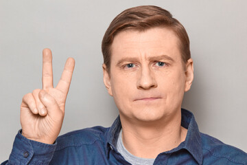 Portrait of happy mature man showing peace or victory sign