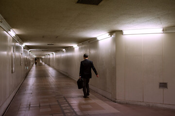 Back view of business man walking in dark underground...