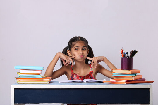 little indian girl thinking or dreaming during preparing homework. with stack of books