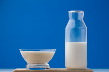 cup of milk with bottle on wood, blue background