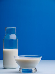 cup of milk with bottle on wood, blue background