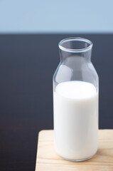 transparent glass milk bottle, on wood, blue background